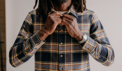 fit model buttoning up The Ledge Shirt in River Plaid