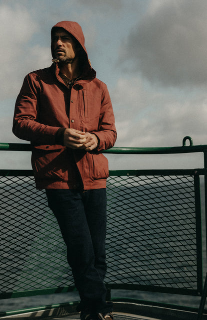 Model standing on the deck of a boat, wearing The Explorer Jacket in Red Wine Dry Wax.