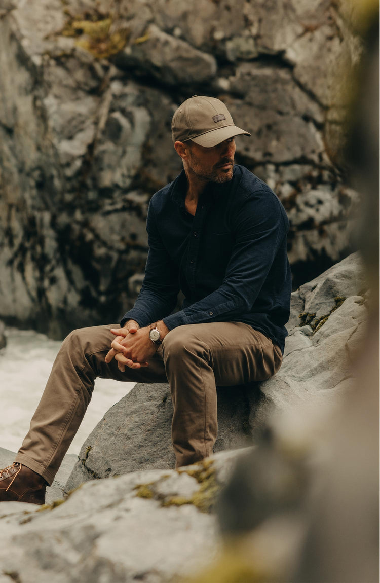 fit model sitting on a rock wearing The Jack in Heather Marine Pincord