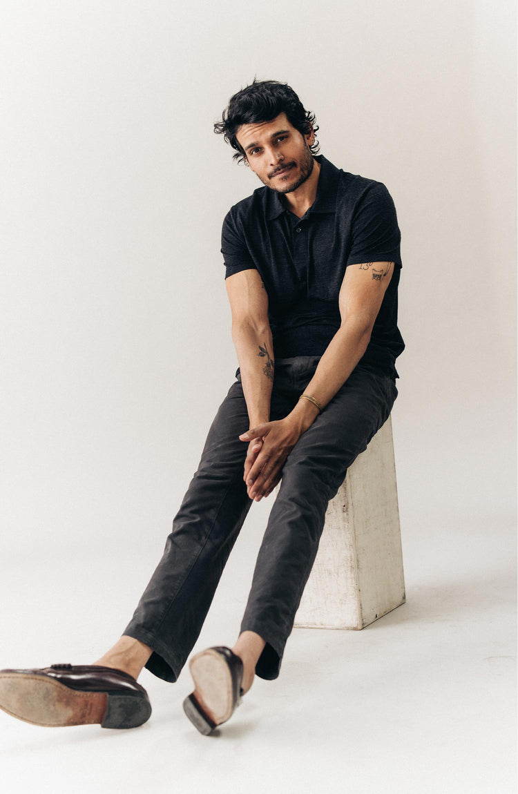 fit model sitting wearing The Merino Polo in Heather Black