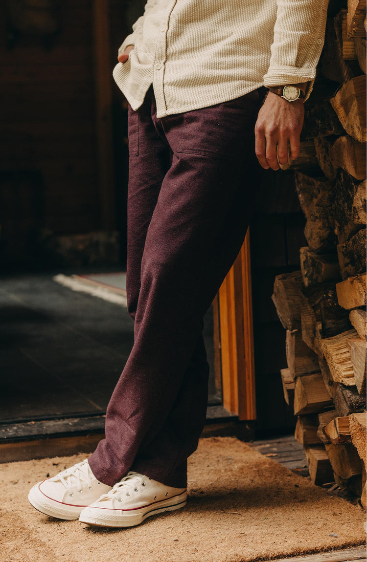 fit model leaning against a wood pile wearing The Breakwater Pant in Nutmeg Donegal