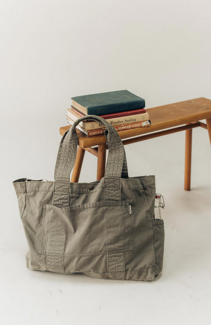 editorial image of The Foundation Tote in Organic Smoked Olive next to a bench