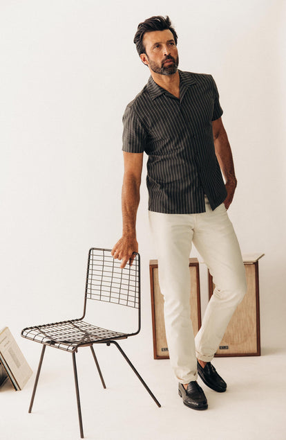 fit model posing next to a chair wearing The Short Sleeve Davis Shirt in Kelp Stripe