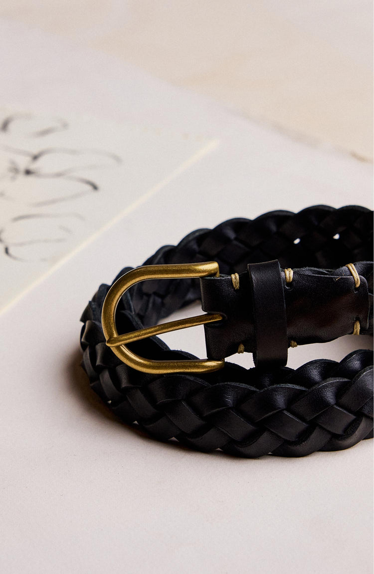 editorial image of The Braided Belt in Black rolled up on paper