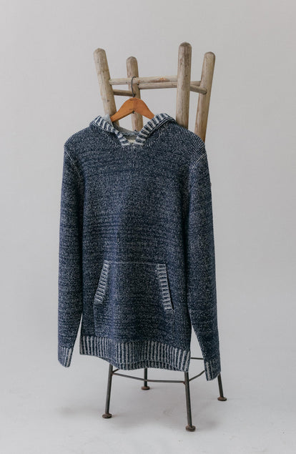 editorial image of The Headland Pullover Sweater in Marled Navy hanging on a stool