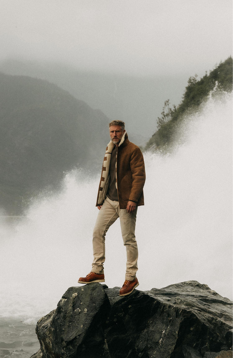 fit model standing on a rock wearing The High Plains Coat in Walnut Shearling