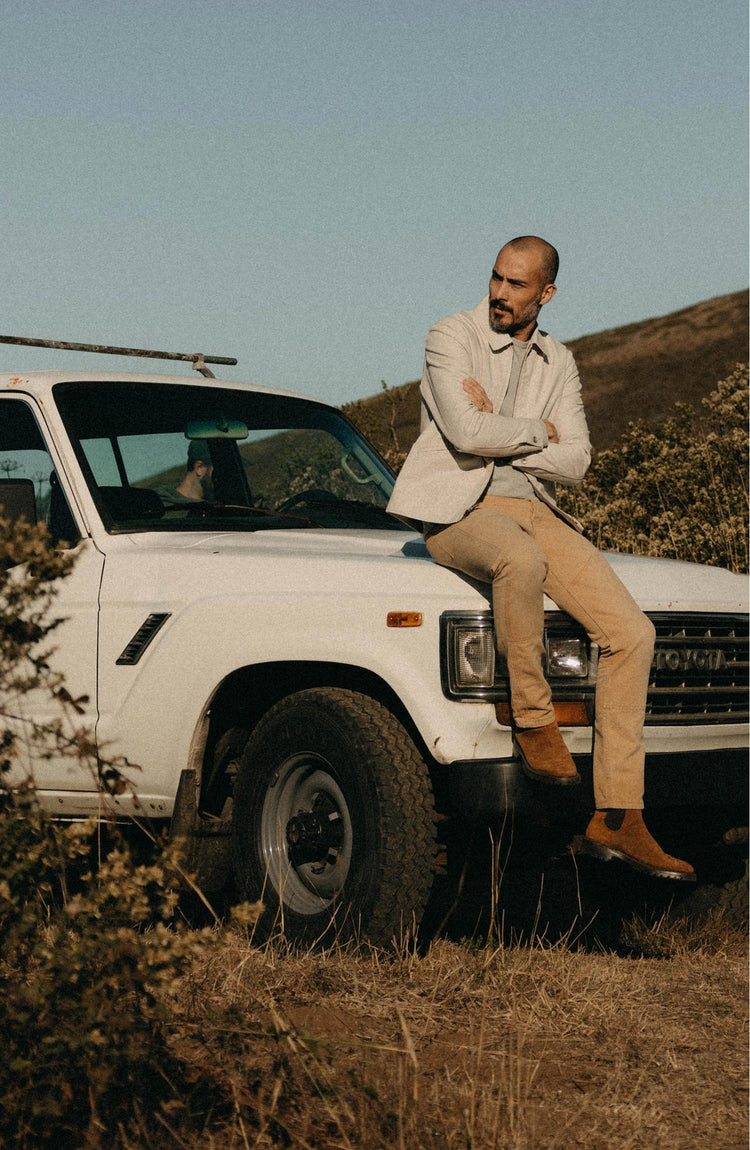 fit model sitting on a car wearing The Shifter Jacket in Stone Pigment Canvas