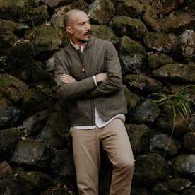 fit model leaning against the wall wearing The Bomber Jacket in Fatigue Olive Dry Wax, Outerwear by Taylor Stitch