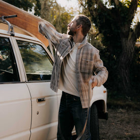 fit model posing near a car wearing The Cutter Overshirt in Grey Plaid, Wovens by Taylor Stitch