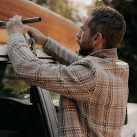 fit model posing by a car wearing The Cutter Overshirt in Grey Plaid, Wovens by Taylor Stitch