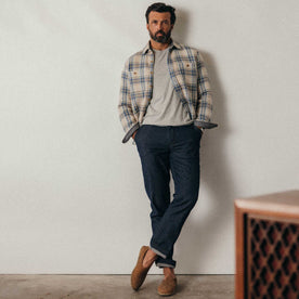 fit model leaning against the wall wearing The Cutter Overshirt in Sandbar Plaid, Wovens by Taylor Stitch