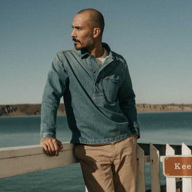 fit model leaning against the wall wearing The Milton Pullover in Washed Selvedge Denim, Wovens by Taylor Stitch