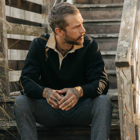 fit model sitting wearing The Rugby Shirt in Coal, Knits by Taylor Stitch