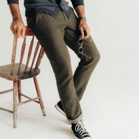 fit model leaning against a chair wearing The Carmel Pant in Heather Olive Cotton Linen, Bottoms by Taylor Stitch