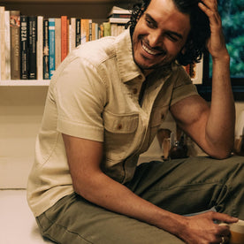 fit model sitting wearing The Short Sleeve Officer Shirt in Dune Double Cloth, Wovens by Taylor Stitch