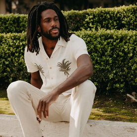 fit model sitting wearing The Short Sleeve Davis Shirt in Natural Palm Embroidery, Wovens by Taylor Stitch