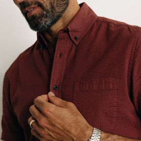 fit model buttoning up The Short Sleeve Jack in Dried Cherry Seersucker, Wovens by Taylor Stitch