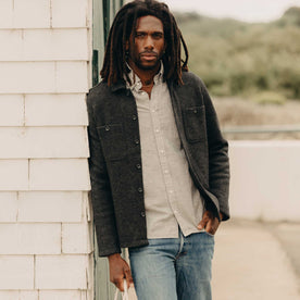 fit model leaning against the wall wearing The Evans Overshirt in Charcoal Birdseye Wool, Wovens by Taylor Stitch