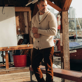 fit model adjusting the cuff on The Fisherman Shawl Cardigan in Heather Oat Merino, Knits by Taylor Stitch