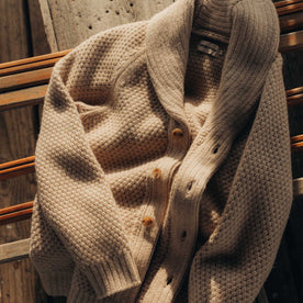 editorial image of The Fisherman Shawl Cardigan in Heather Oat Merino on a bench, Knits by Taylor Stitch