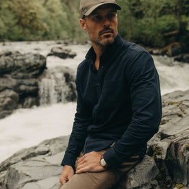 fit model sitting on a rock wearing The Jack in Heather Marine Pincord, Wovens by Taylor Stitch