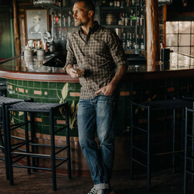 fit model leaning against a bar wearing The Jack in Mulch Plaid, Wovens by Taylor Stitch