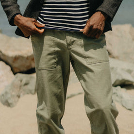 fit model sitting wearing The Surplus Pant in Field Olive Reverse Sateen, Bottoms by Taylor Stitch