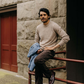 fit model leaning against a railing wearing The Lodge Sweater in Sand Donegal, Knits by Taylor Stitch