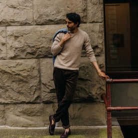 fit model leaning against a railing wearing The Lodge Sweater in Sand Donegal, Knits by Taylor Stitch