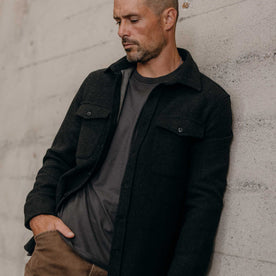 fit model leaning against the wall wearing The Maritime Shirt Jacket in Heather Charcoal, Wovens by Taylor Stitch