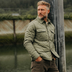 fit model leaning against a pole wearing The Miller Shirt Jacket in Smoked Olive Dry Wax, Outerwear by Taylor Stitch