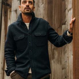 fit model leaning against the wall wearing The Connor Overshirt in Dark Navy Boucle, Wovens by Taylor Stitch