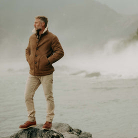 fit model standing on a rock wearing The High Plains Coat in Walnut Shearling, Outerwear by Taylor Stitch