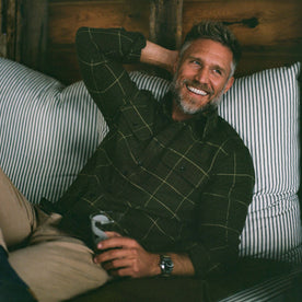 fit model sitting wearing The Ledge Shirt in Olive Plaid, Wovens by Taylor Stitch