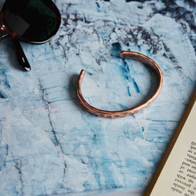 editorial image of The Hammered Cuff in Copper on a marble table, Accessories by Taylor Stitch