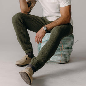 fit model sitting on a rope wearing The Quilted Apres Pant in Heather Fatigue Olive Jersey, Bottoms by Taylor Stitch