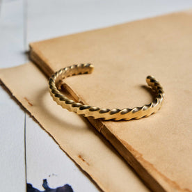 editorial image of The Twisted Cuff in Brass on a piece of paper, Accessories by Taylor Stitch