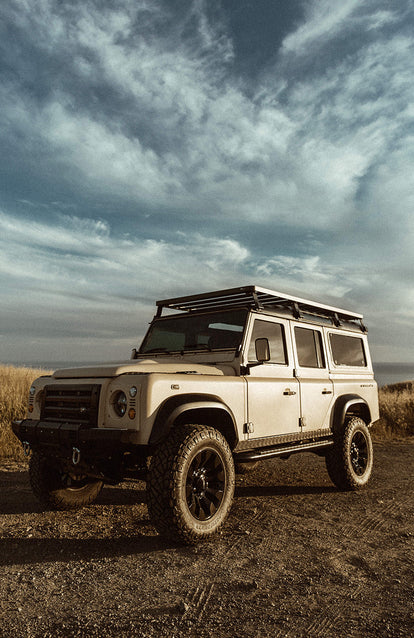 Looking up at a Landrover in three-quarter view, with sky as the background.