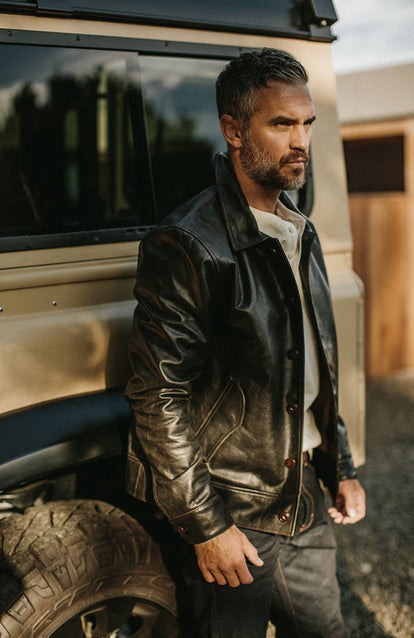 Modeling a leather jacket, leaning against a Landrover.