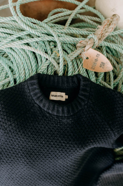 The Fisherman Sweater in Dark Navy Merino on top of dock lines