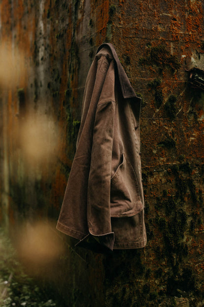 The Upland Jacket in Aged Penny Chipped Canvas hanging on a wall