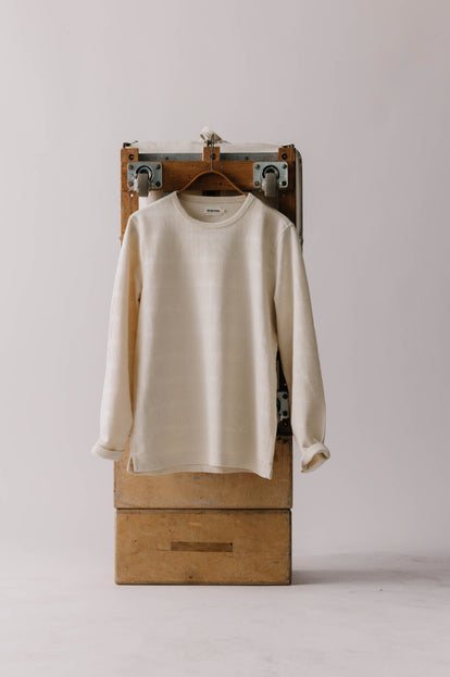 The Morgan Crewneck in Natural Slub Stripe hanging on a stack of apple boxes